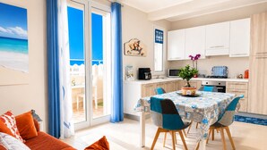 Ein modernes Wohnzimmer mit Sofa, Essbereich mit Tisch und Küche mit Schränken und Geräten.