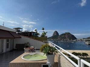A rooftop terrace with a hot tub, seating area, and a view of a bay with boats and a mountain. - PENTHOUSE BOTAFOGO Panoramic penthouse with large terrace in Rio de Janeiro (Rio de Janeiro)