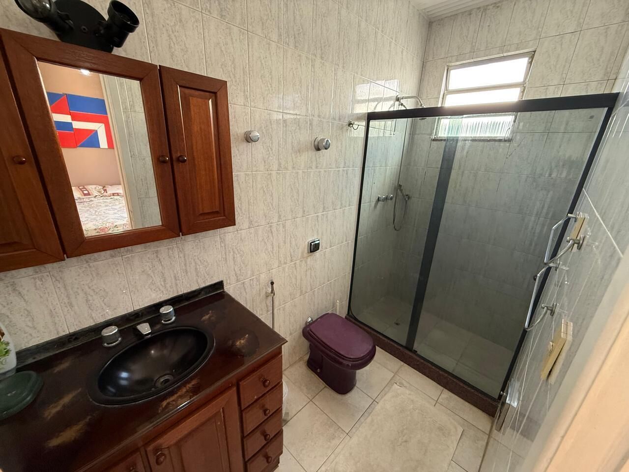 A bathroom with a glass shower enclosure, a wooden vanity with a sink, and a toilet.
