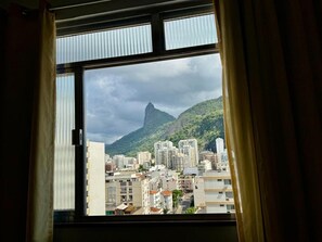 A window view of a cityscape with buildings and a prominent mountain.
