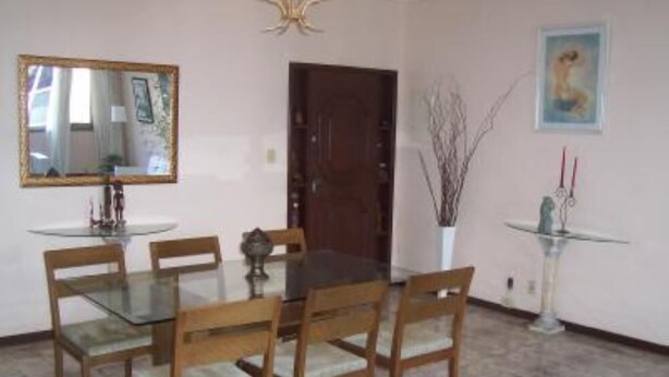 Un comedor con una mesa de vidrio, sillas de madera, un espejo y una puerta.