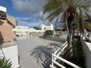 A rooftop terrace with a palm tree, seating area, and a view of the cityscape. - PENTHOUSE BOTAFOGO Panoramic penthouse with large terrace in Rio de Janeiro (Rio de Janeiro)