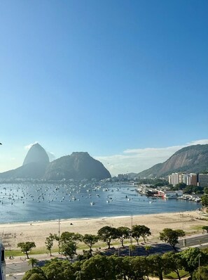 A coastal cityscape with a prominent mountain, a beach, and numerous boats.