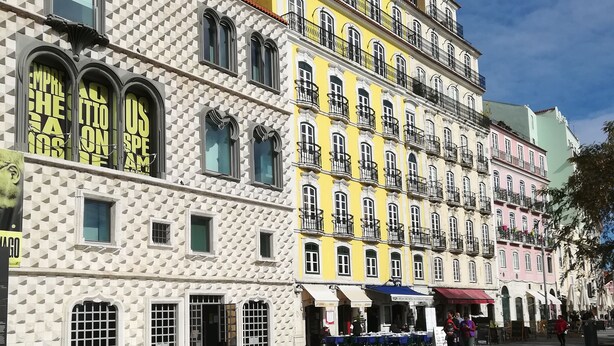 Un edificio histórico con varios balcones y ventanas arqueadas, situado en una plaza empedrada.