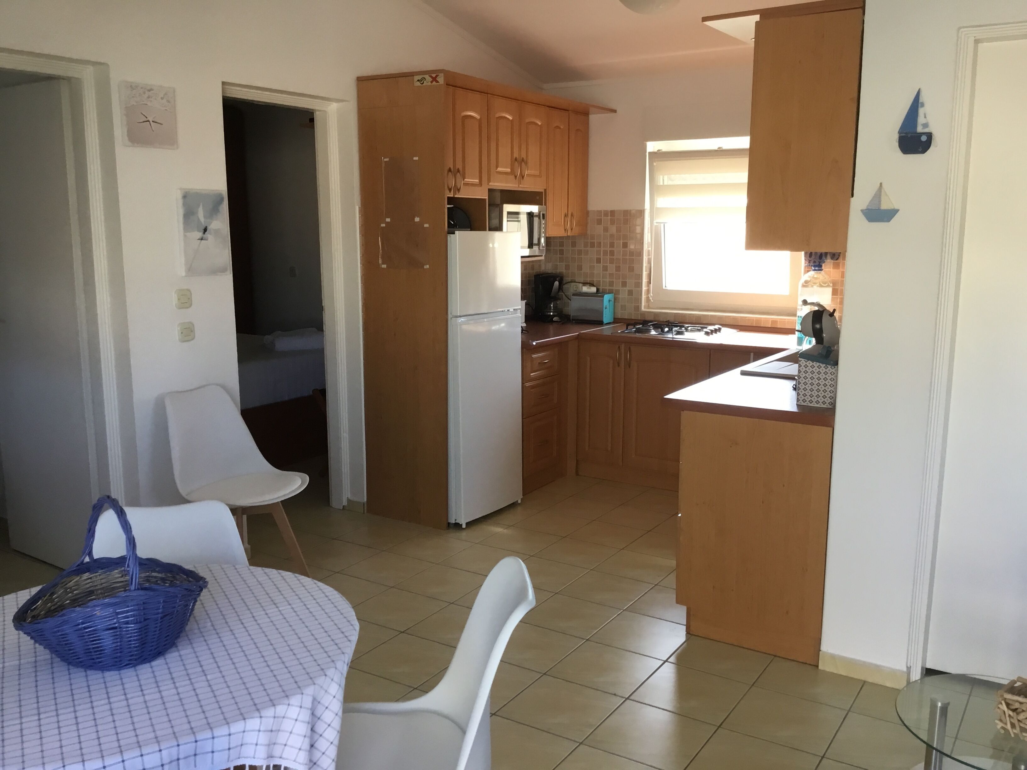 Une cuisine de taille réduite, dotée de meubles en bois, d’un réfrigérateur blanc et d’un coin repas avec une table et des chaises.