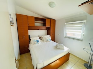 Ein Schlafzimmer mit einem Bett, einem Holzschrank und einem Fenster mit Jalousien.