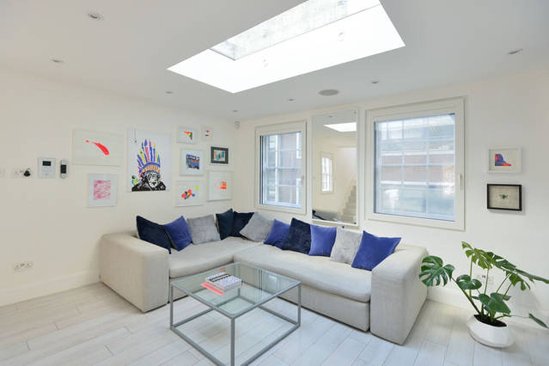 A modern living room with a sectional sofa, a glass coffee table, and a potted plant.