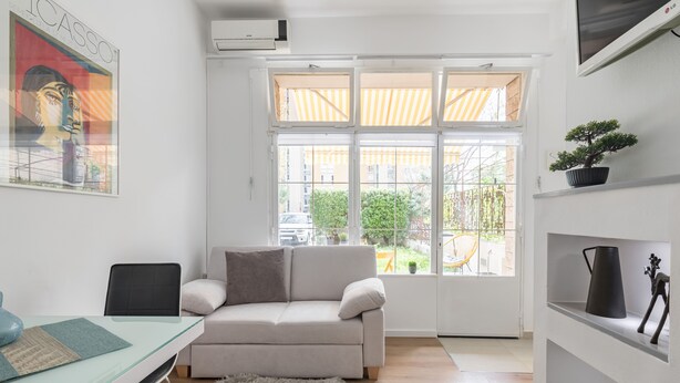 Een moderne woonkamer met een glazen tafel, een bank, een pluizig vloerkleed en een potplant.