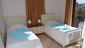 Un dormitorio con dos camas, una mesita de noche y una ventana con cortinas.