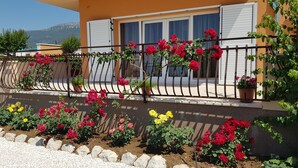 A balcony with red roses and yellow flowers, a house with white shutters, and a mountain view in the background. -  Luxury villa with private heated pool, hot tub,  mini golf,  spacious inter... (Kaštel Kambelovac)
