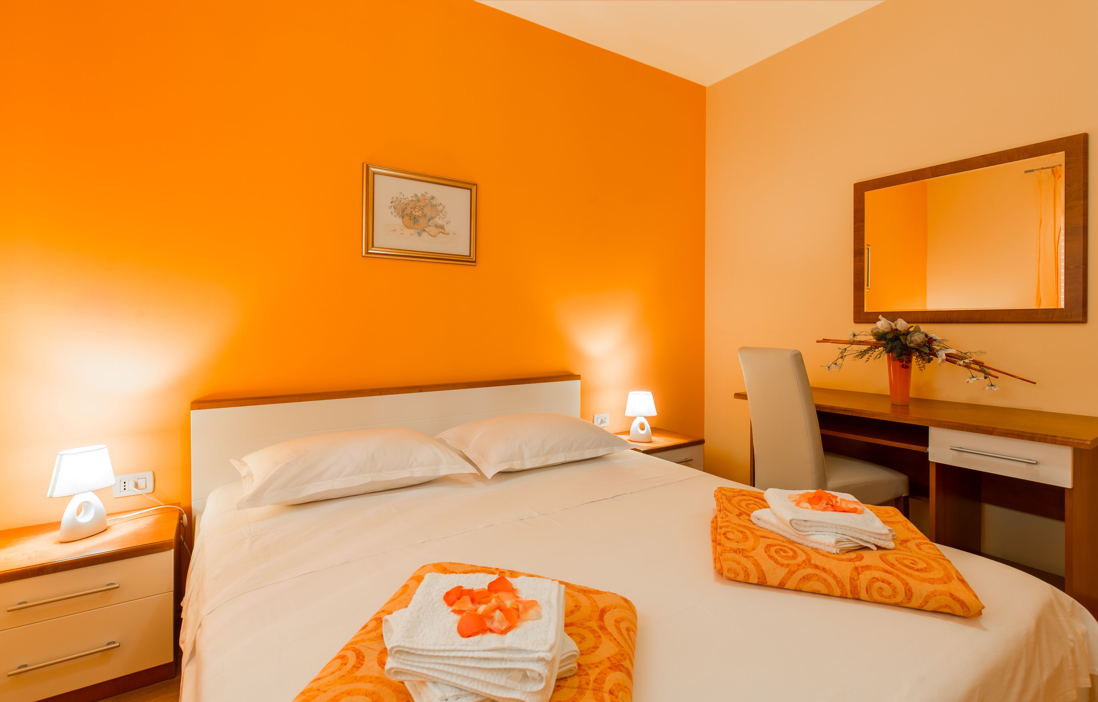 A hotel room with a large bed, two bedside tables, a desk, and a chair.