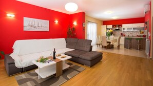 A modern living room with a sectional sofa, a small coffee table, and a dining area with a kitchen in the background. -  Luxury villa with private heated pool, hot tub,  mini golf,  spacious inter... (Kaštel Kambelovac)
