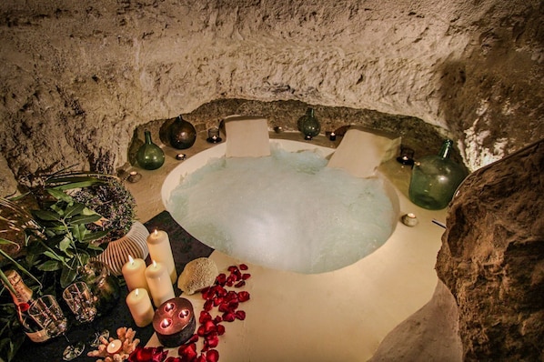 Ein Wellnessbad mit Kerzen, Rosenblüten und dekorativen Vasen.
