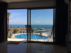 Un balcón con vistas a una piscina y al mar.