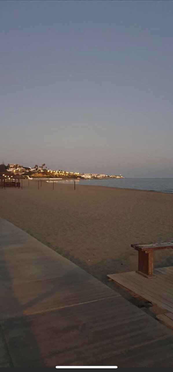 Una playa con un paseo de madera y un banco.