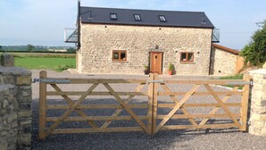 A stone house with a gated entrance, a small porch with potted plants, and a view of the countryside. - Beautiful Country Cottage Pet Friendly  Sleeps 7 Near Cardiff (Cardiff)