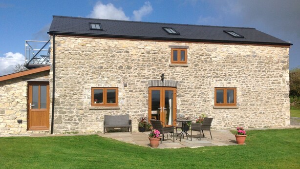 A stone house with a large door, two windows, and a patio with outdoor furniture. - Beautiful Country Cottage Pet Friendly  Sleeps 7 Near Cardiff (Cardiff)