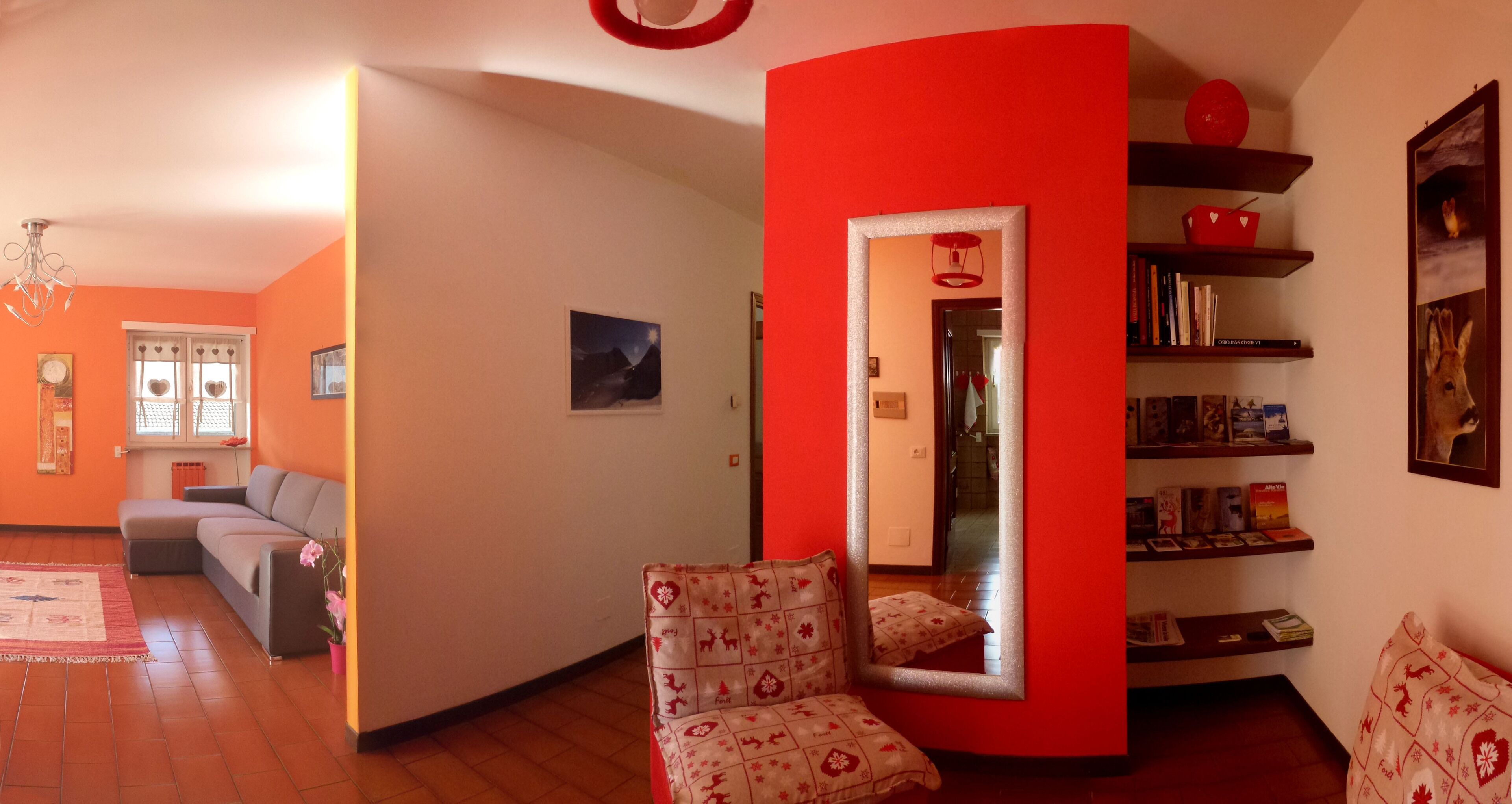 Un salon avec un canapé, des fauteuils, une bibliothèque et un mur d’accent de couleur rouge.