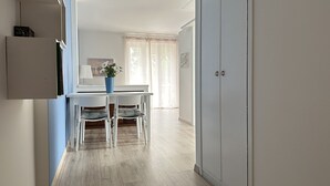 A modern kitchen with white cabinets, a dining table with two chairs, and a window with sheer curtains. - The Seagull apartment Sirmione | Spa & Garda Lake (Sirmione)