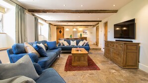 A living room with blue sofas, a wooden coffee table, and a TV on a cabinet. - Atherstone Farm Cottage - charming thatched cottage, sleeps 4 guests in 2 rooms (Ilminster)
