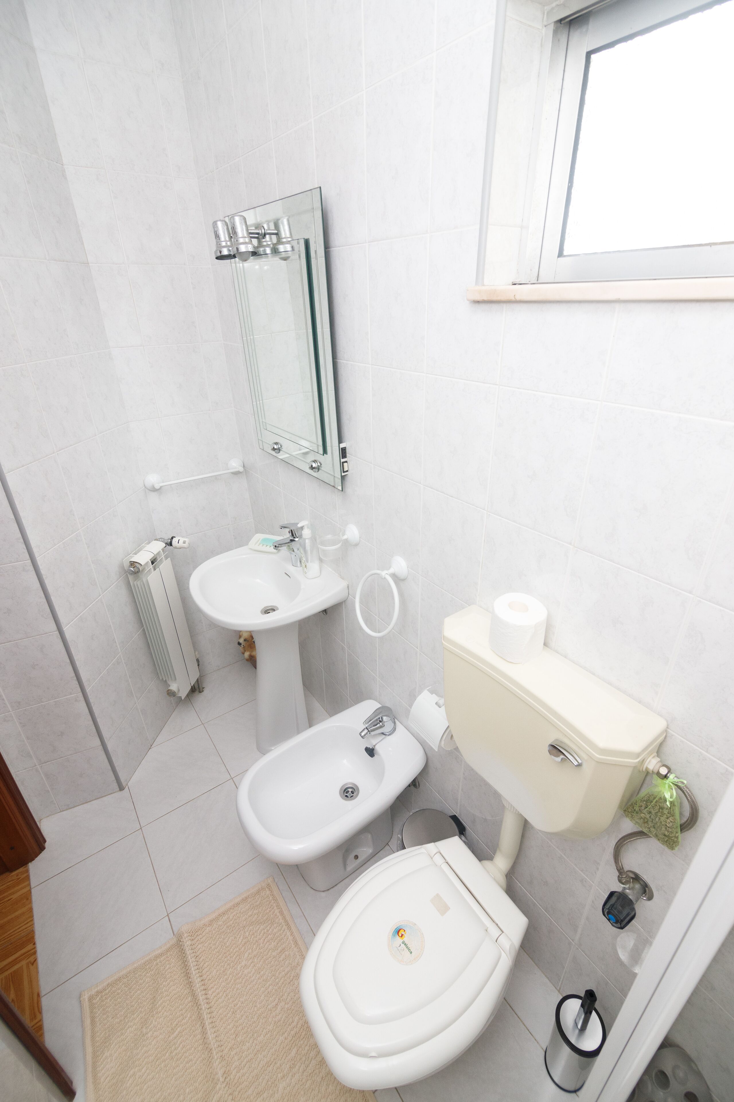 Un baño moderno con inodoro, bidé, lavamanos y espejo.