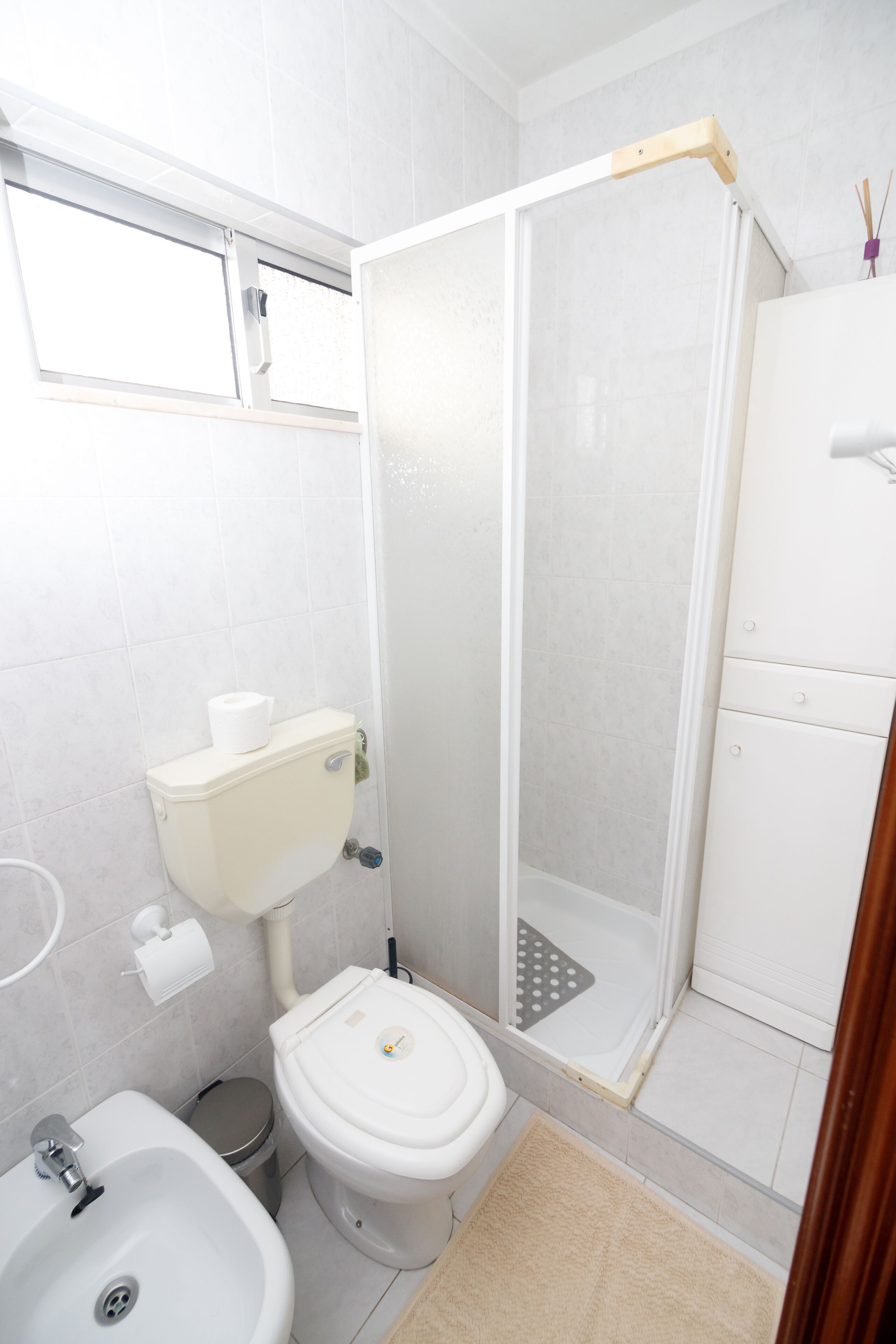 Un bagno con WC, bidet, lavandino e cabina doccia in vetro.