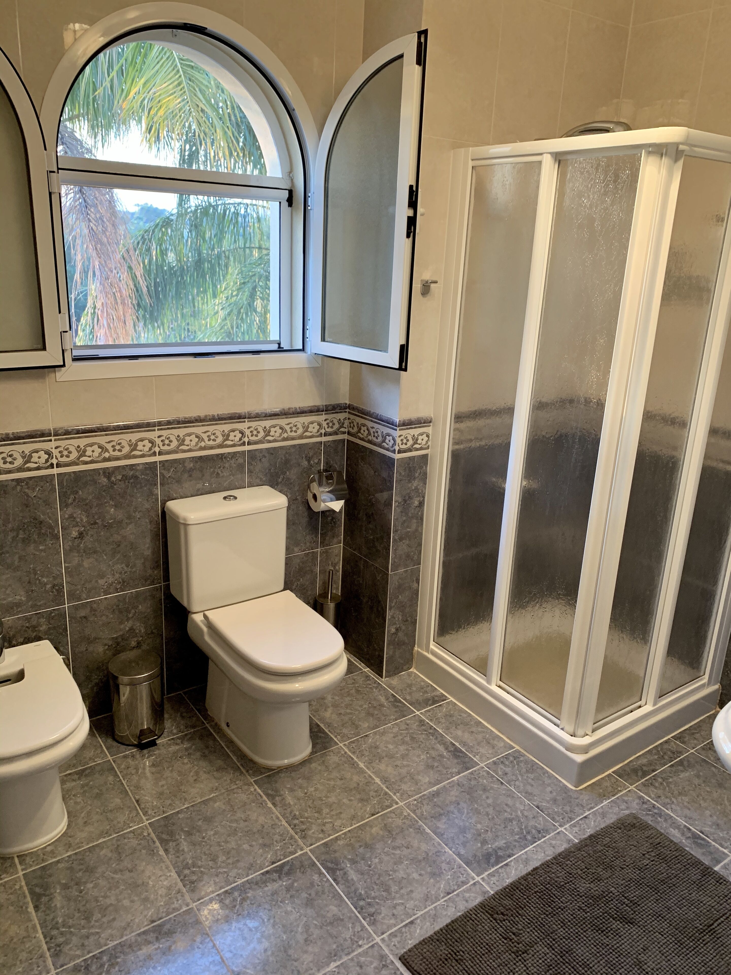 Un baño con inodoro, bidé y ducha con mampara de vidrio.
