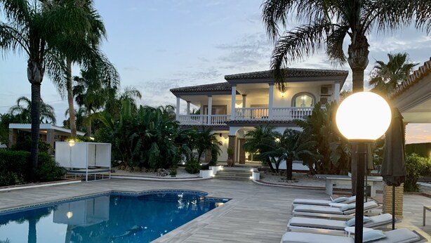 A swimming pool with lounge chairs, a well-lit building with a balcony, and tropical landscaping. - Luxury villa w/ stunning views in 2 acres of rural countryside - 30m from coast (Alhaurin el Grande, Málaga)
