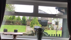 A room with a window overlooking a garden. There is a table with a vase and a box on it. - PLAN YOUR ISLAND ESCAPE TO THE BEAUTIFUL SCOTTISH ISLE OF CUMBRAE (Millport)