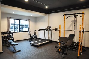 A gym with a treadmill, stationary bike, weight bench, and a squat rack. - C Room (Chomchan) at Airport (Chiang Mai)