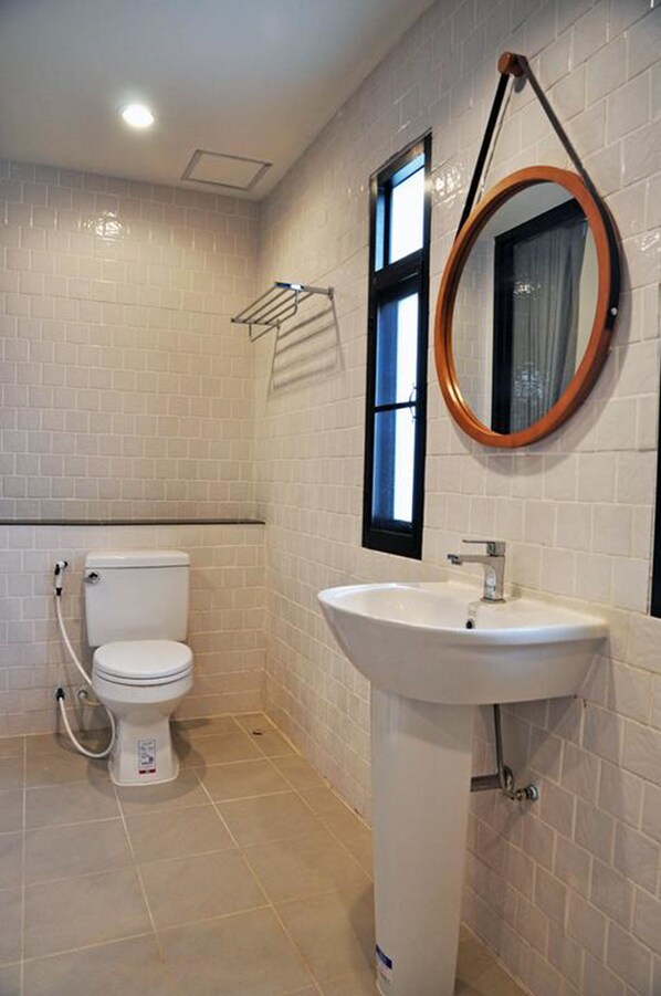 A bathroom with a toilet, sink, and a window with a towel rack.