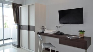 A modern hotel room with a sliding door closet, a desk with a flat-screen TV, a chair, and a small potted plant. - C Room (Chomchan) at Airport (Chiang Mai)
