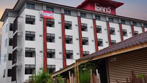 A multi-story building with a prominent red and white facade, featuring balconies and large windows. - C Room (Chomchan) at Airport (Chiang Mai)