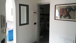 A hallway with a mirror, a framed picture, and a blue chair. - Vacation Dimaro-Val di Sole CIN: IT022233C2QJN7YDD9 Apartment A (Dimaro)