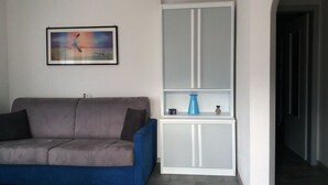 A living room with a grey sofa, a white cabinet with glass doors, and a framed picture on the wall. - Vacation Dimaro-Val di Sole CIN: IT022233C2QJN7YDD9 Apartment A (Dimaro)