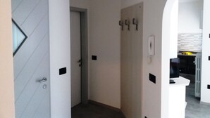 A narrow hallway with a door on the left, a light switch, and a phone on the wall. - Vacation Dimaro-Val di Sole CIN: IT022233C2QJN7YDD9 Apartment A (Dimaro)
