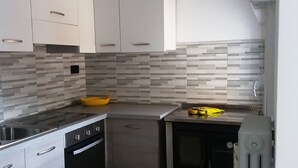A modern kitchen with white cabinets, a tiled backsplash, and stainless steel appliances. - Vacation Dimaro-Val di Sole CIN: IT022233C2QJN7YDD9 Apartment A (Dimaro)