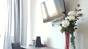 A modern room with a desk, chair, TV, coffee maker, and a vase with flowers. - Modern and cozy Italian experience (Mestre)