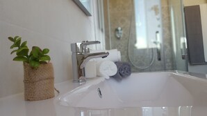 A bathroom with a white sink, a plant in a burlap pot, and towels. - Modern and cozy Italian experience (Mestre)