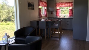 Een moderne keuken met een centraal eiland, barstoelen en een eettafel.