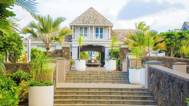 A grand entrance with a stone staircase leading to a house with a triangular roof and a balcony.