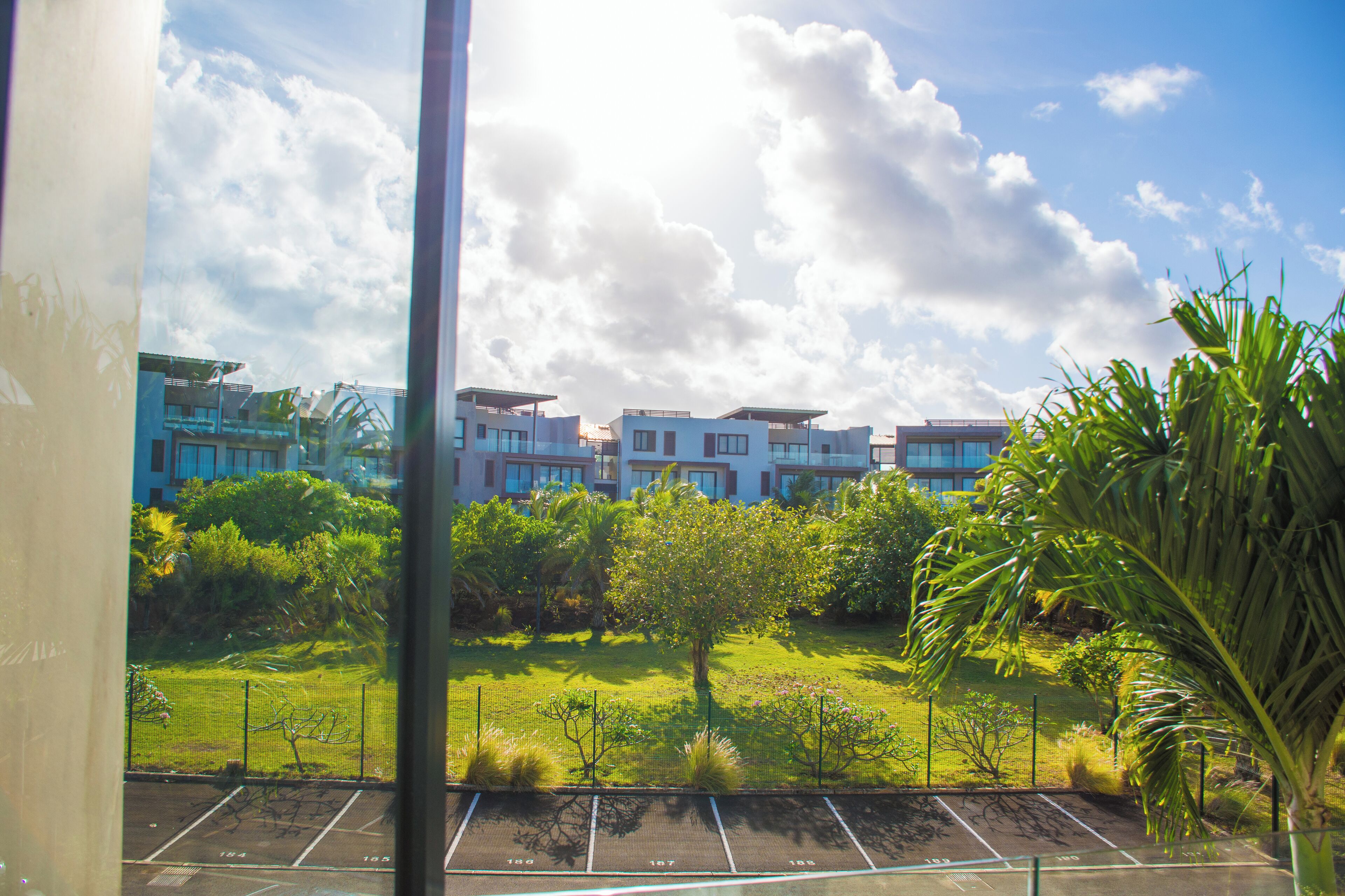 A residential area with modern buildings, a grassy lawn, and a parking lot.