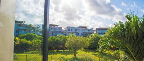 A residential area with modern buildings, a grassy lawn, and a parking lot.