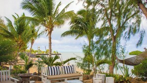 A beachside lounge with a sofa, chairs, a table, and a hammock.
