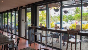 An indoor dining area with large windows, wooden chairs, and tables.