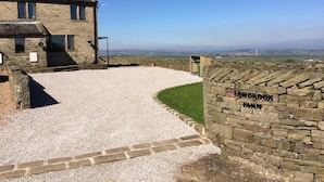 A stone building with a gravel driveway leading to a stone wall with the inscription "WILBROOK FARM". - Law Brook Farm cottage with stunning views . (Hudderfield)