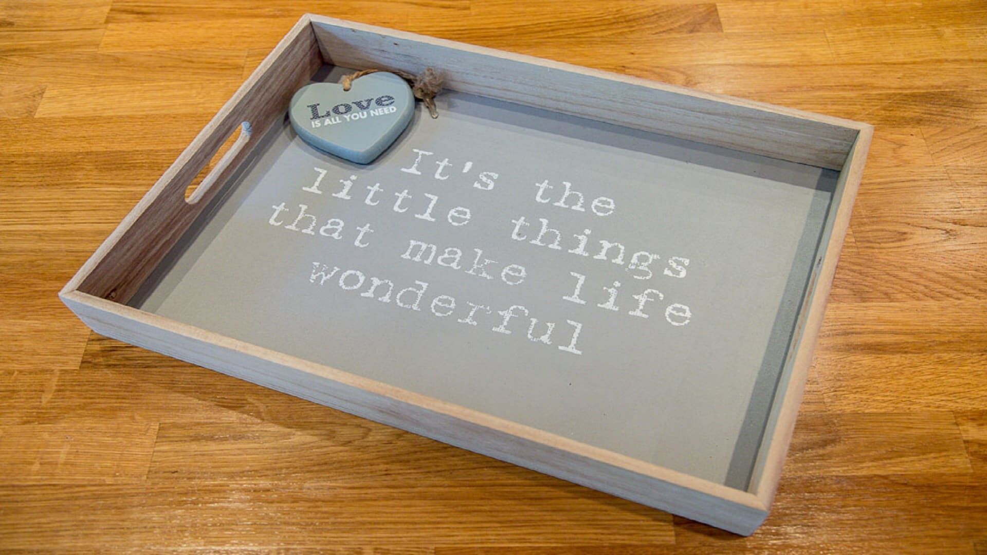 Een lijst met een inspirerende quote en een hartvormige decoratie met de tekst 'Love is all you need'.