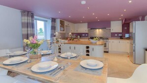 A modern kitchen with white cabinets, a wooden island, and a dining area set for a meal.