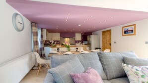 A modern kitchen with a dining area, a purple ceiling, and a clock on the wall.