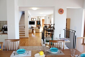 A dining area with a wooden table set for four, a television in the background, and a staircase leading to another level. - Arton Villa with the heated pool in the heart of Istria (Žminj)